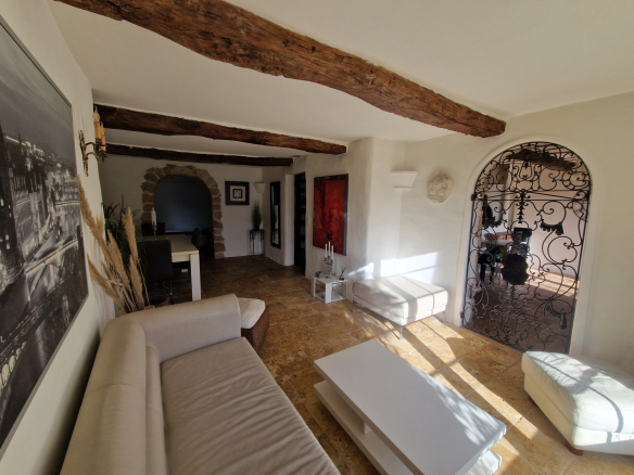 Intérieur lumineux d'une bastide provençale avec poutres apparentes et mobilier moderne.