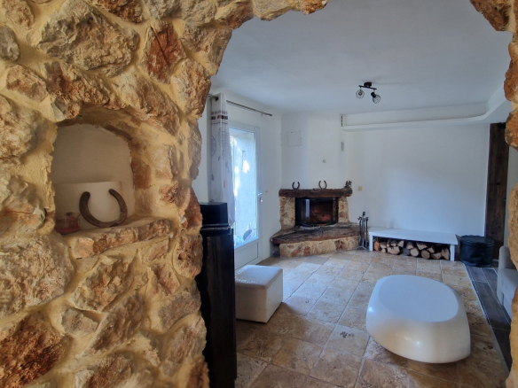 Intérieur d'une bastide provençale avec cheminée en pierre et murs en pierre apparente.