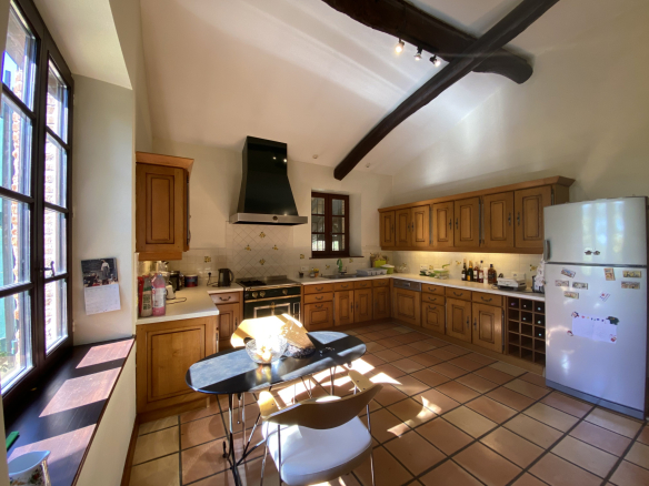Country house kitchen with wooden furniture and tiled floor, lit by natural light.
