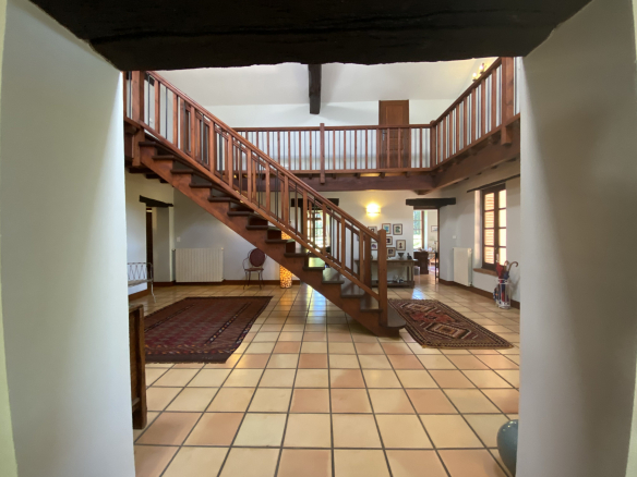 Interior of a country house with a wooden staircase and a tiled floor.
