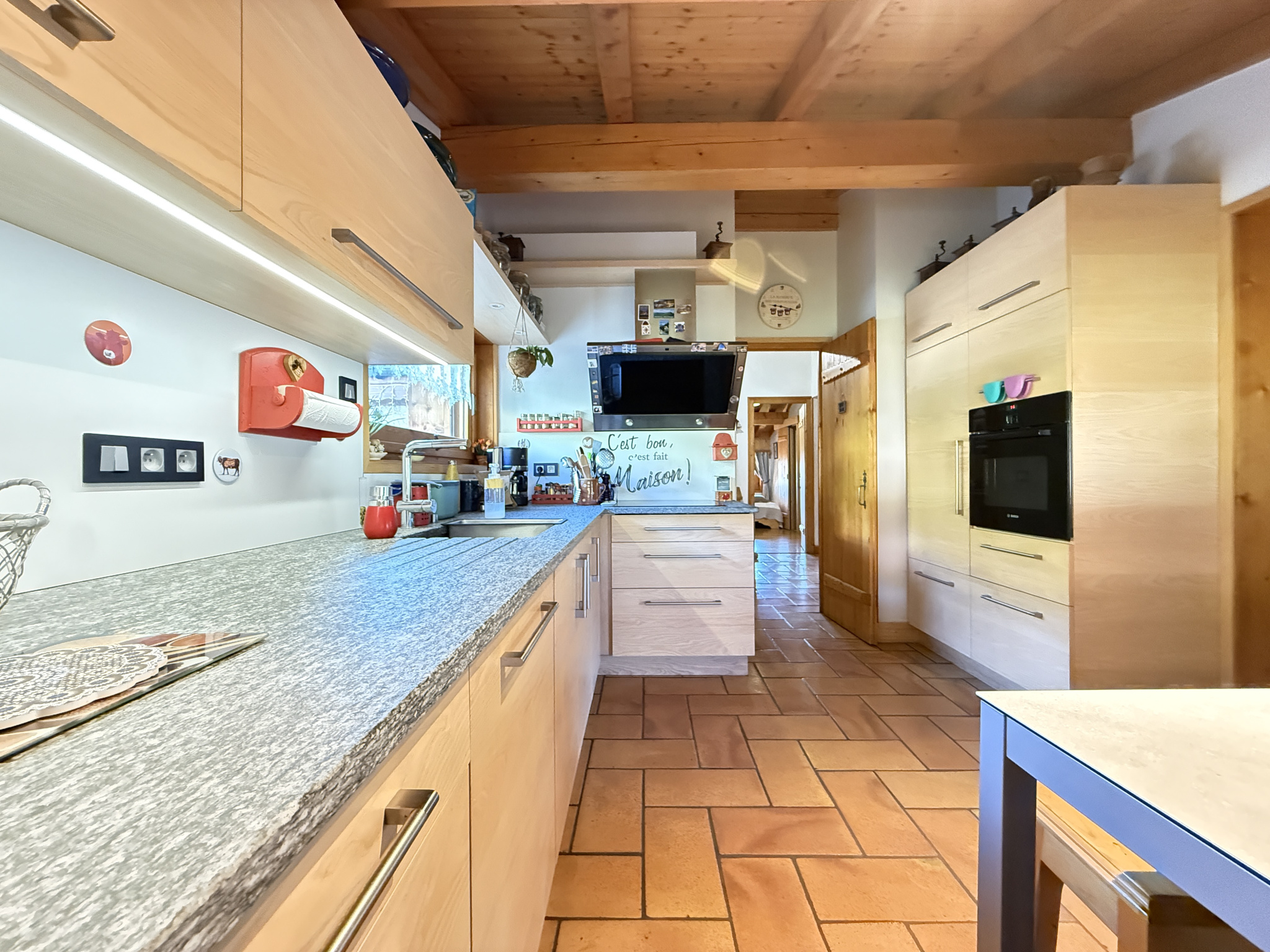 Interior of a modern kitchen in a traditional chalet, with wooden furniture and a granite worktop.