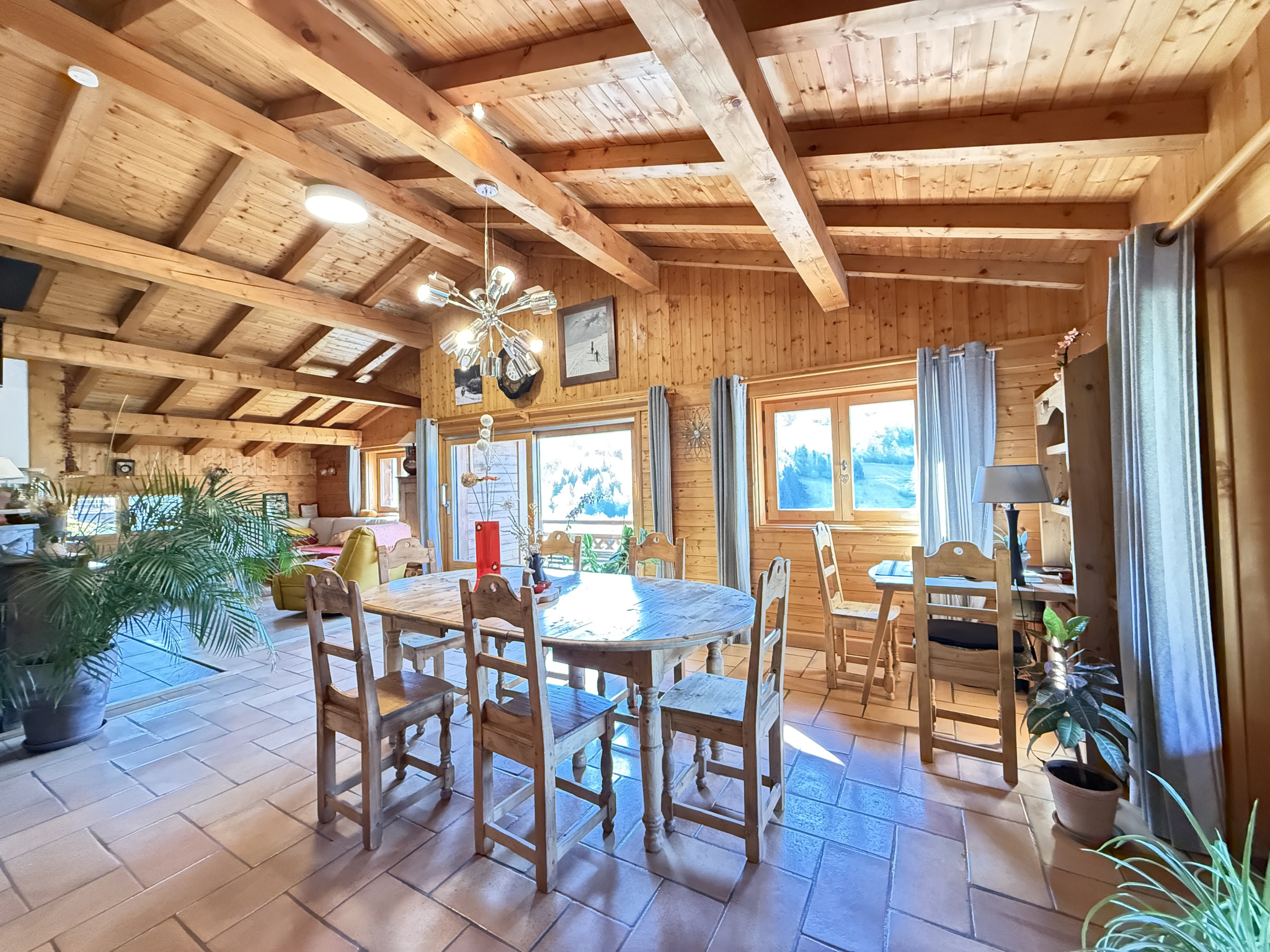 Interior of a traditional chalet with a wooden dining room and bright windows.