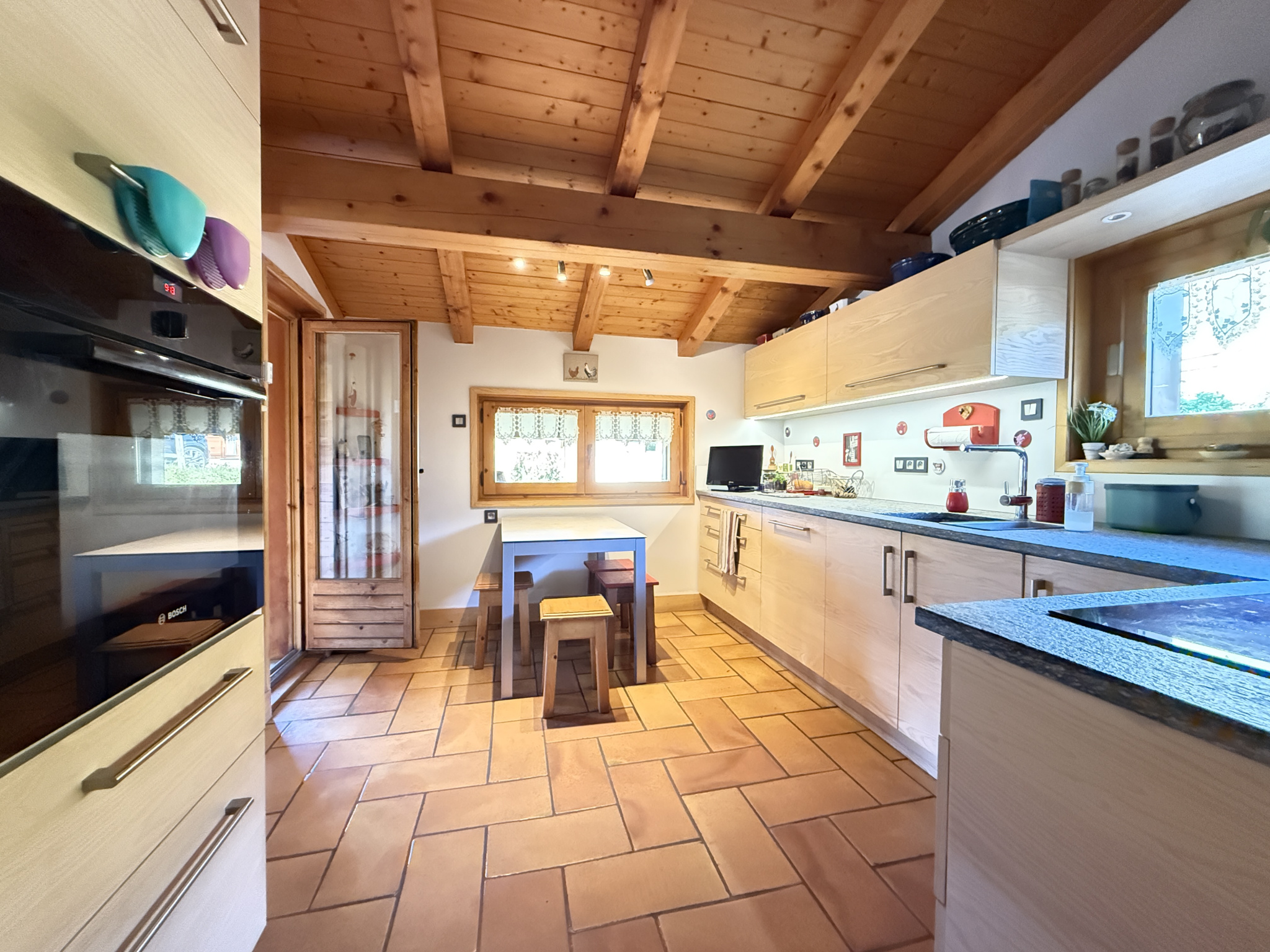 Interior of a traditional chalet with a modern kitchen and wooden dining area.