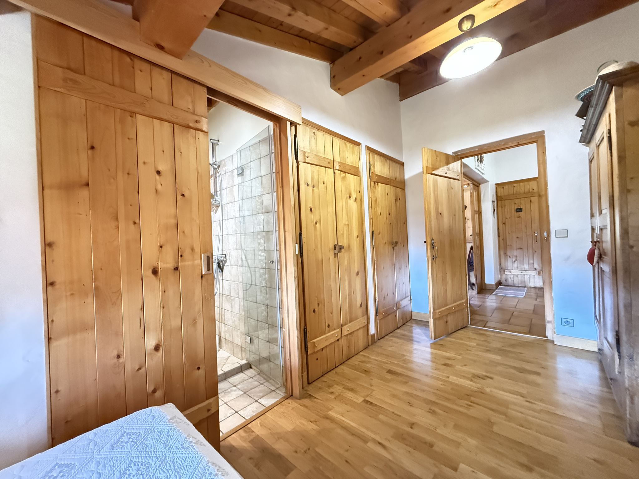 Interior of a traditional chalet with wooden walls and wooden doors, visible bathroom.