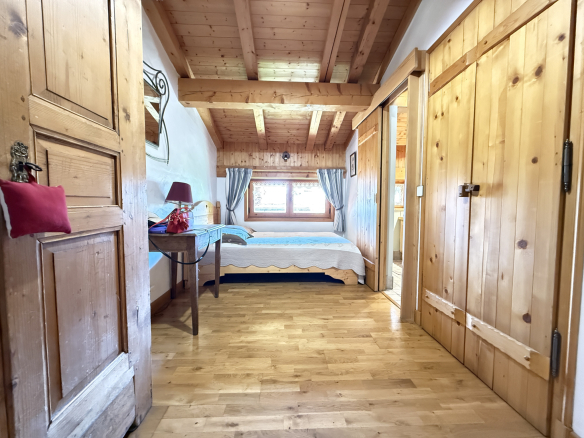 Interior of a traditional wooden chalet with a bedroom and warm furnishings.