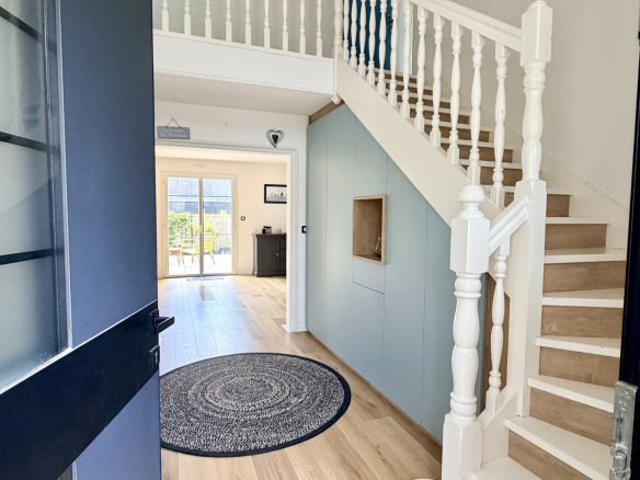 Entrance to a contemporary house with staircase and view of a bright space.