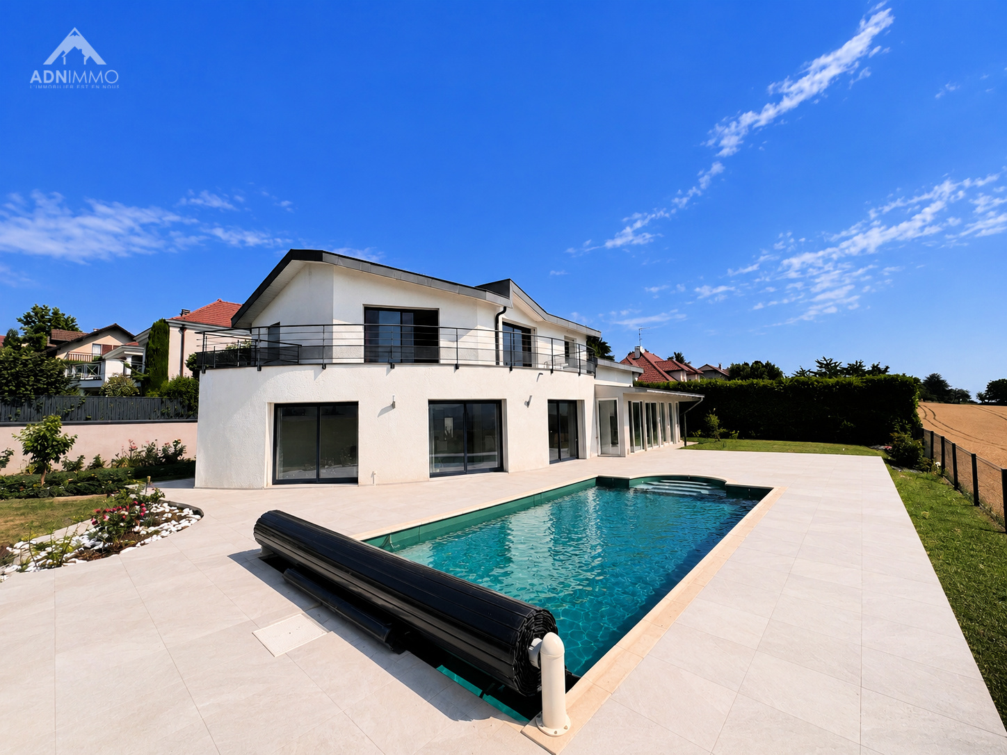 Maison moderne avec piscine à Challex Maison individuelle moderne avec piscine à Challex, vue sur jardin et ciel bleu.