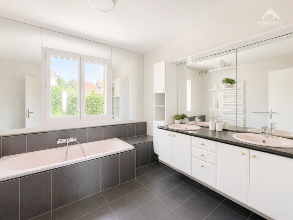 Salle de bain moderne avec baignoire et double vasque dans une maison à Challex.