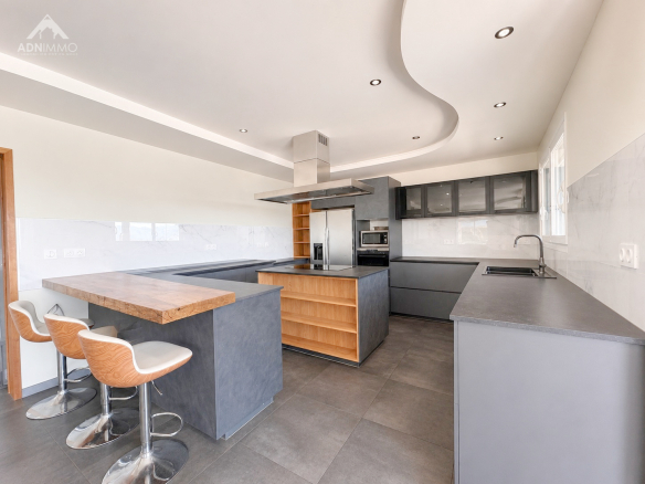 Cuisine moderne et spacieuse d'une maison à Challex, avec îlot central et équipements intégrés.