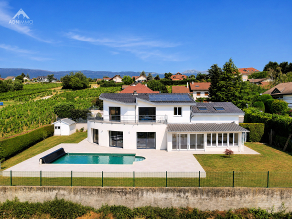 Maison individuelle moderne avec piscine à Challex, vue sur le jardin et les montagnes.