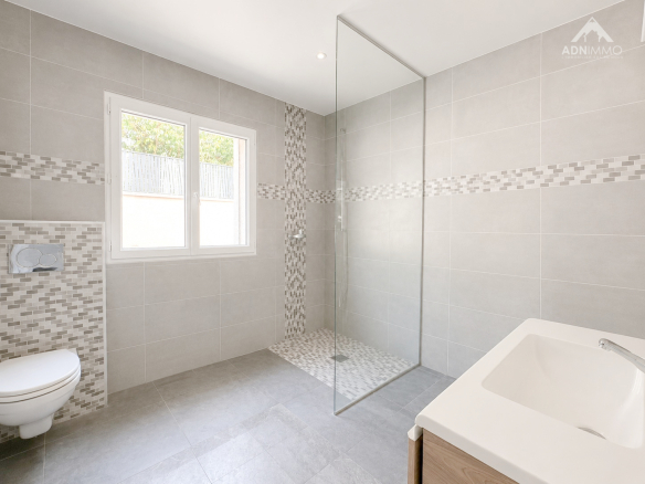 Salle de bain moderne avec douche à l'italienne et baignoire, murs carrelés.