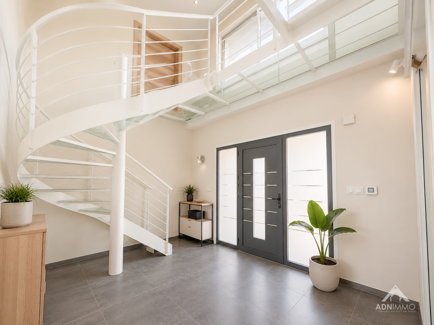 Intérieur d’une maison à Challex Intérieur d'une maison moderne avec un escalier en colimaçon et une entrée lumineuse.