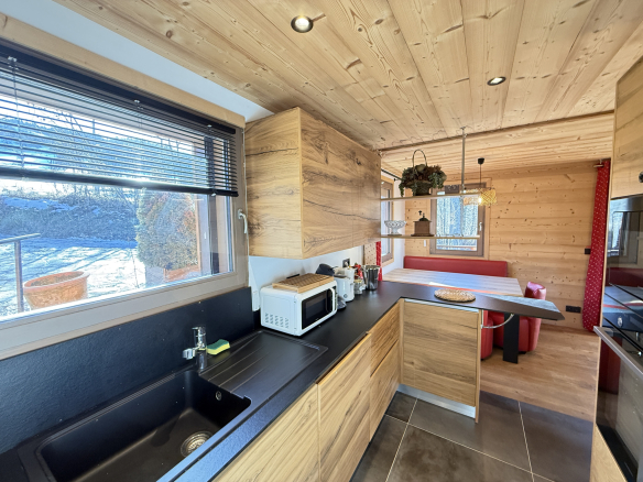 Interior of an alpine chalet in Combloux, modern kitchen with wooden furniture and view of the outside.