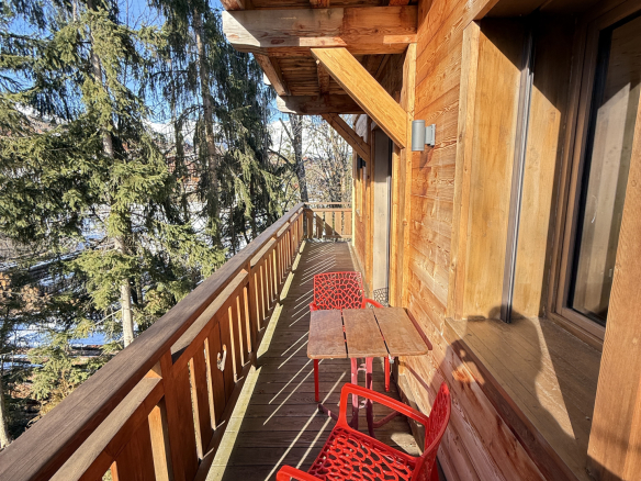 Wooden balcony of an alpine chalet with red chairs in Combloux.
