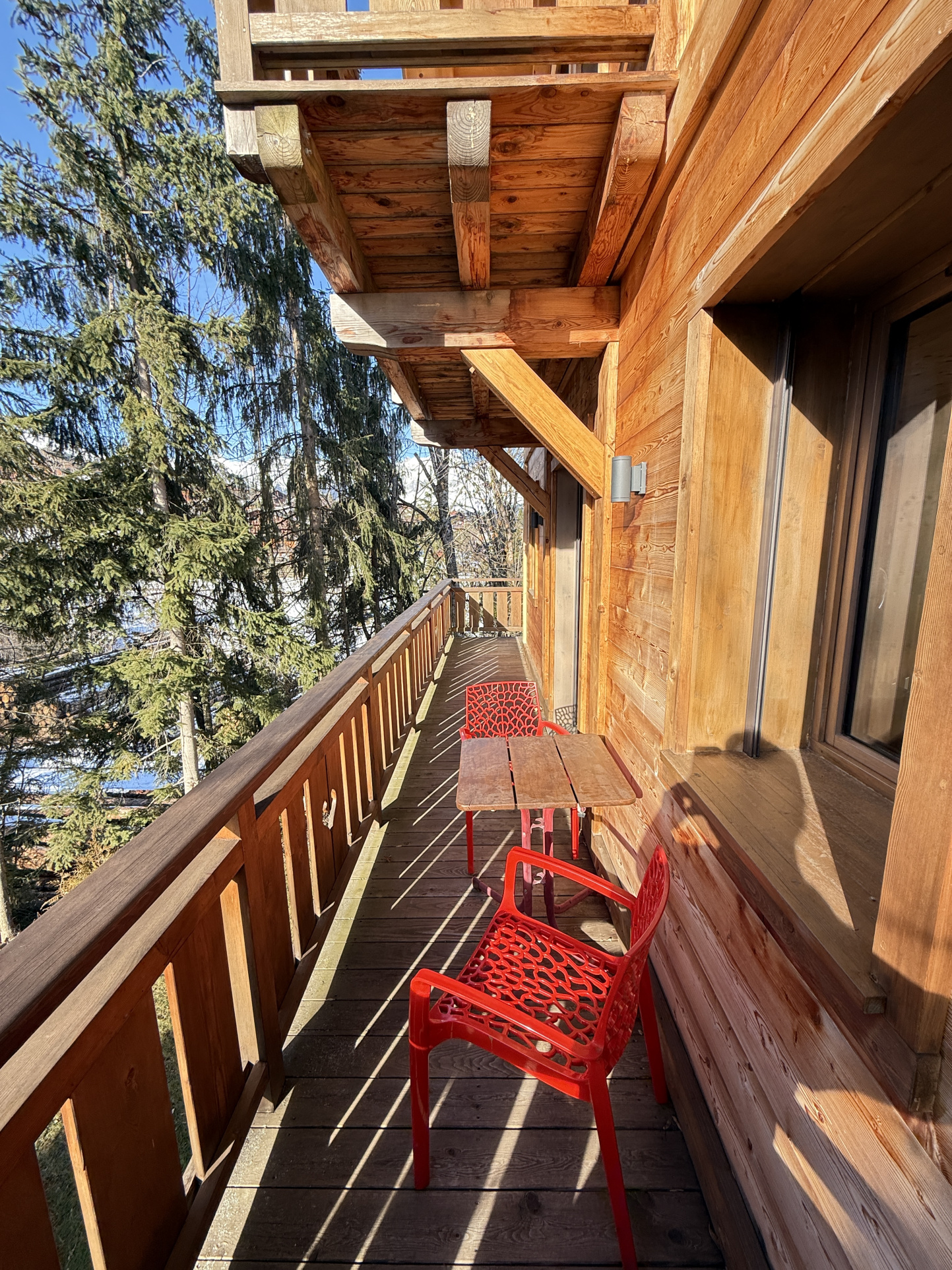 Balcony of a chalet in Combloux Wooden balcony of an alpine chalet with red chairs in Combloux.