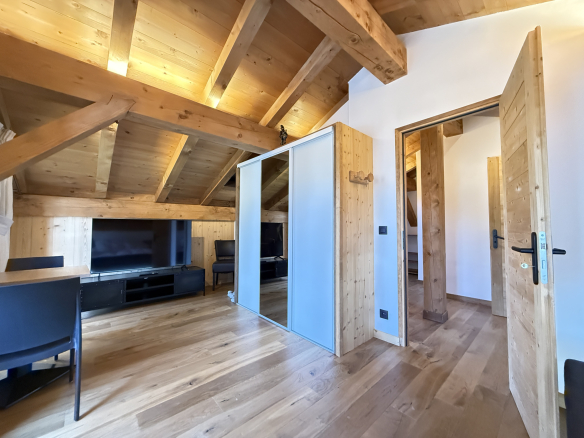 Interior of an alpine chalet in Combloux with wooden beams and bright living space.