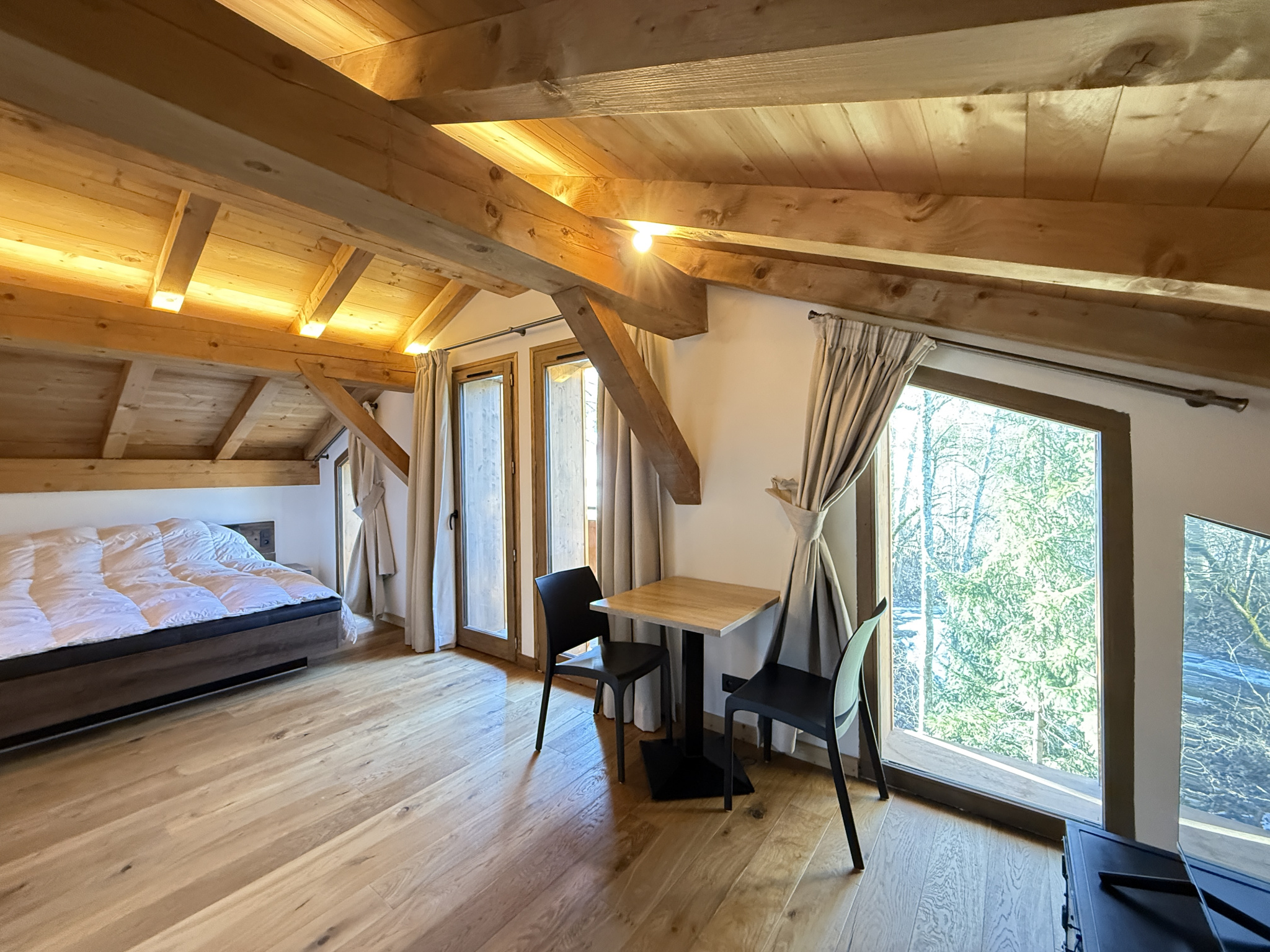 Interior of a chalet in Combloux Interior of an alpine chalet in Combloux, with a bed, a table and a view of nature.