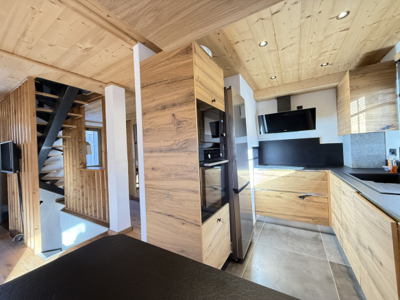 Interior of an alpine chalet with modern kitchen and wooden staircase in Combloux.