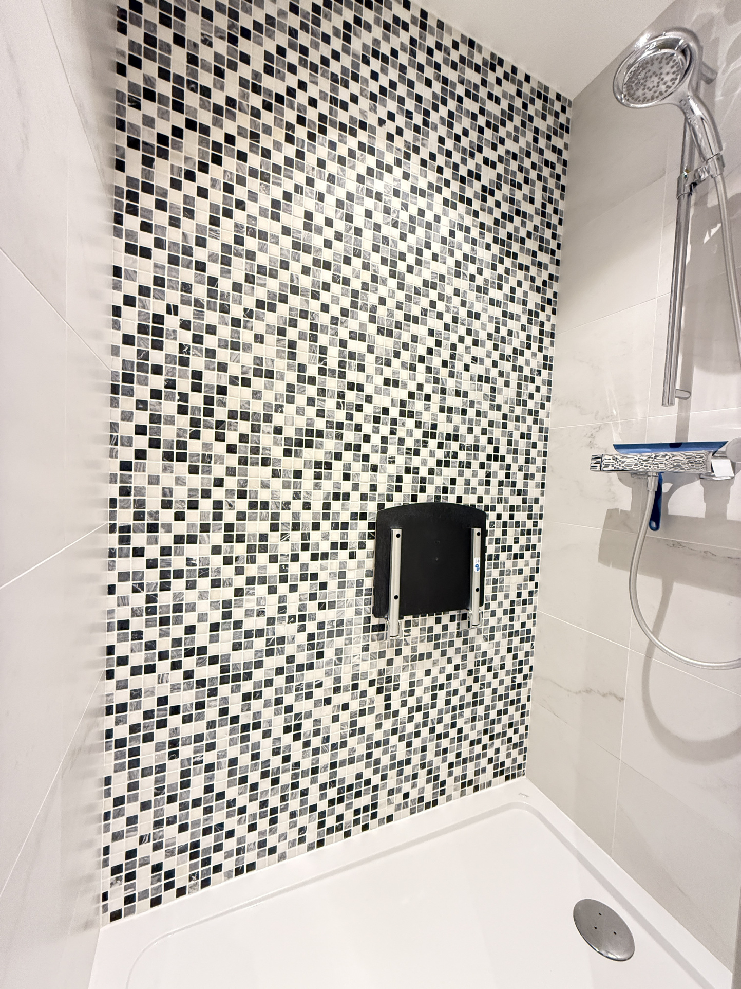 Douche moderne avec carrelage mosaïque Douche avec carrelage en mosaïque noir et blanc dans un appartement.