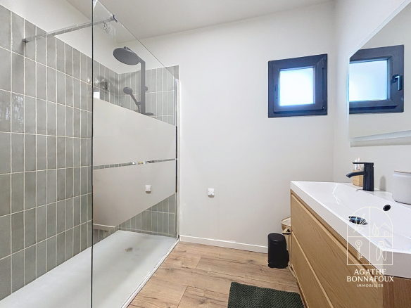 Modern bathroom with walk-in shower and wooden vanity.