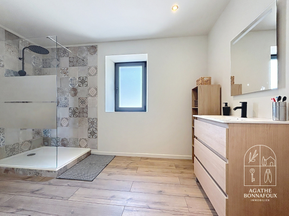 Modern bathroom with walk-in shower and wooden furniture, natural light.
