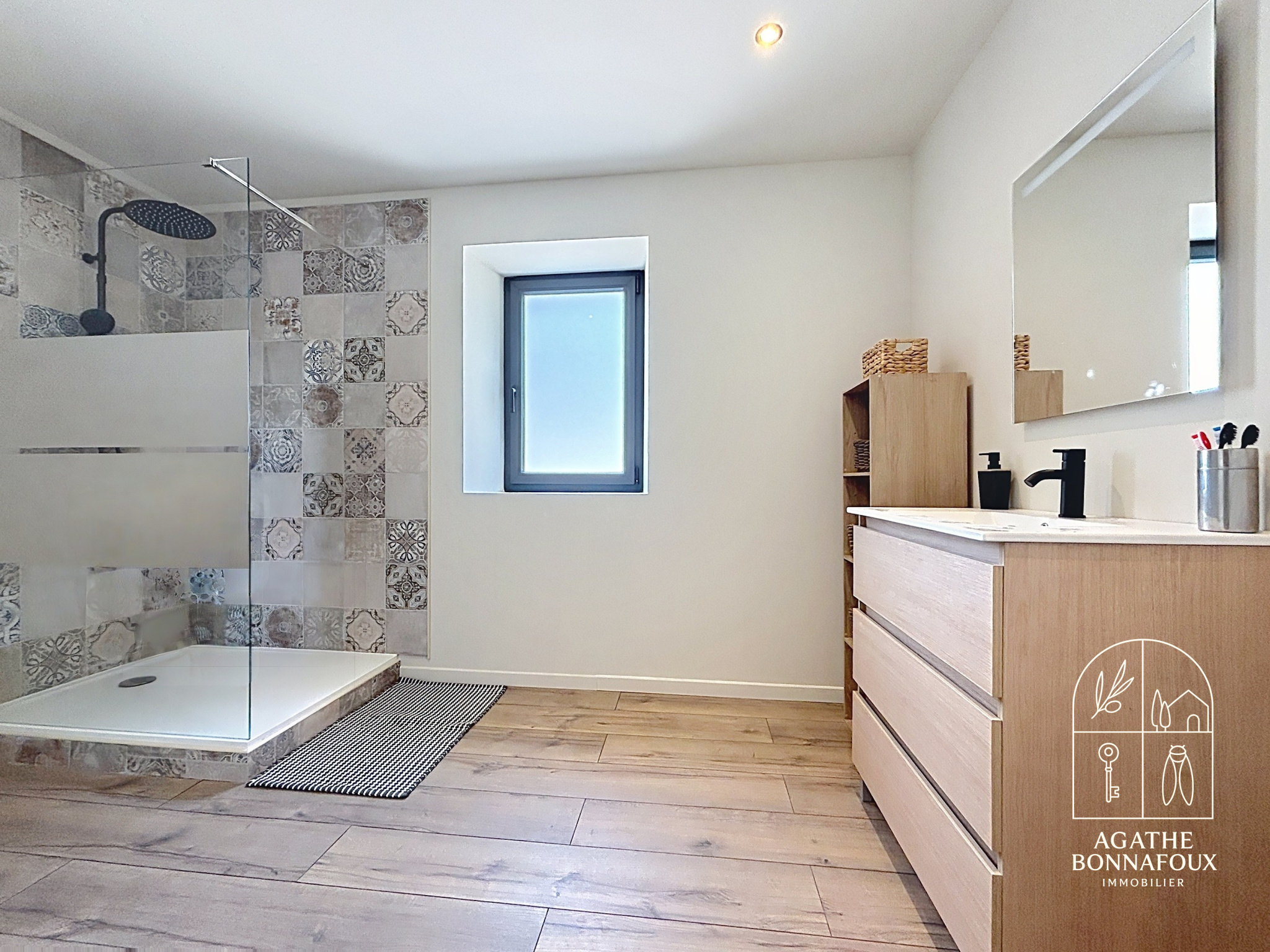 Modern bathroom with walk-in shower and wooden furniture, natural light.