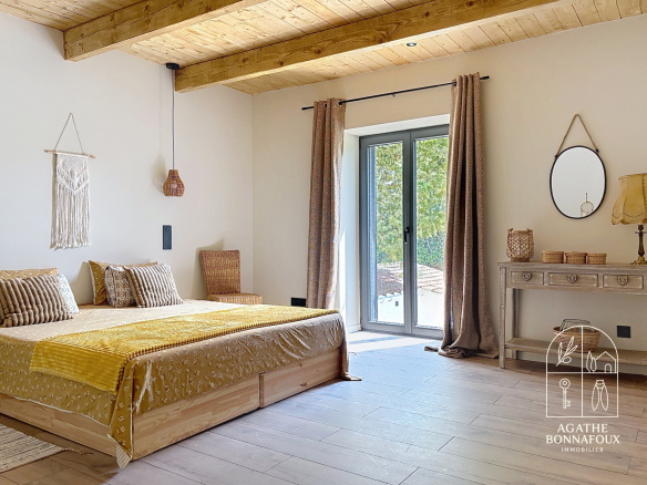 Room in a renovated Provençal farmhouse with bed, wooden decor and access to the outside.