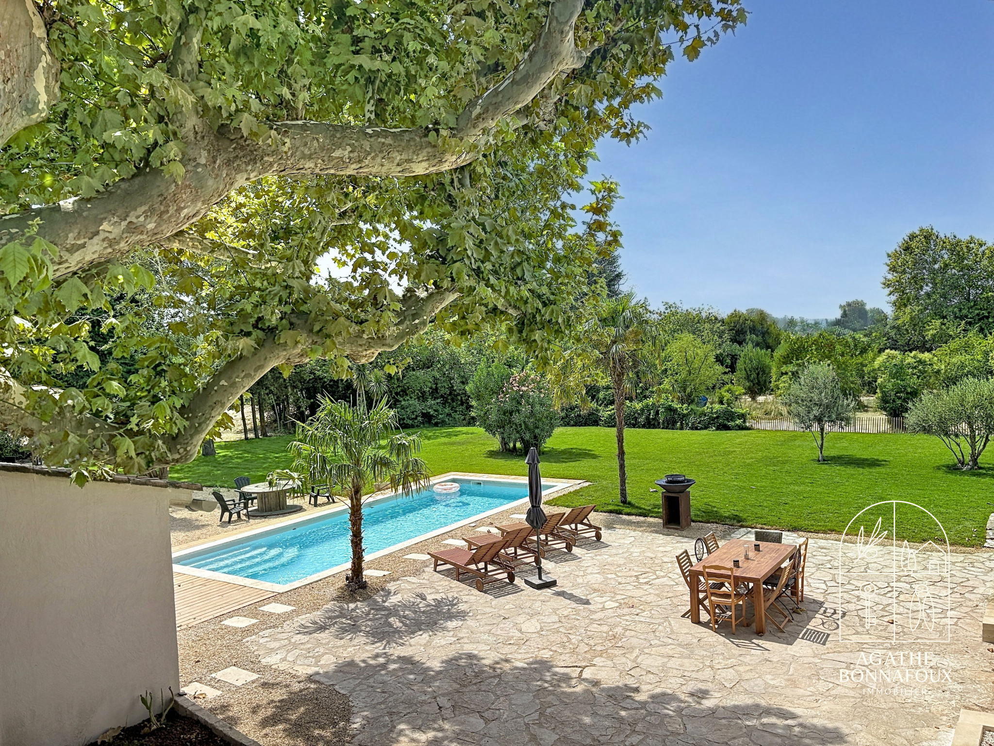 View of a renovated Provençal farmhouse with swimming pool and green garden in Châteaurenard.