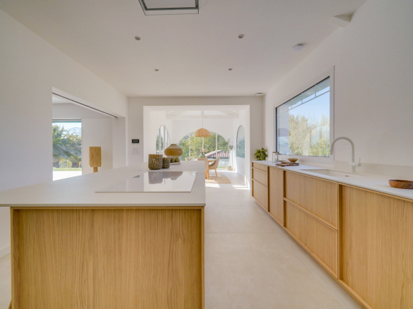 Cuisine moderne et lumineuse avec îlot central et vue sur l'extérieur.