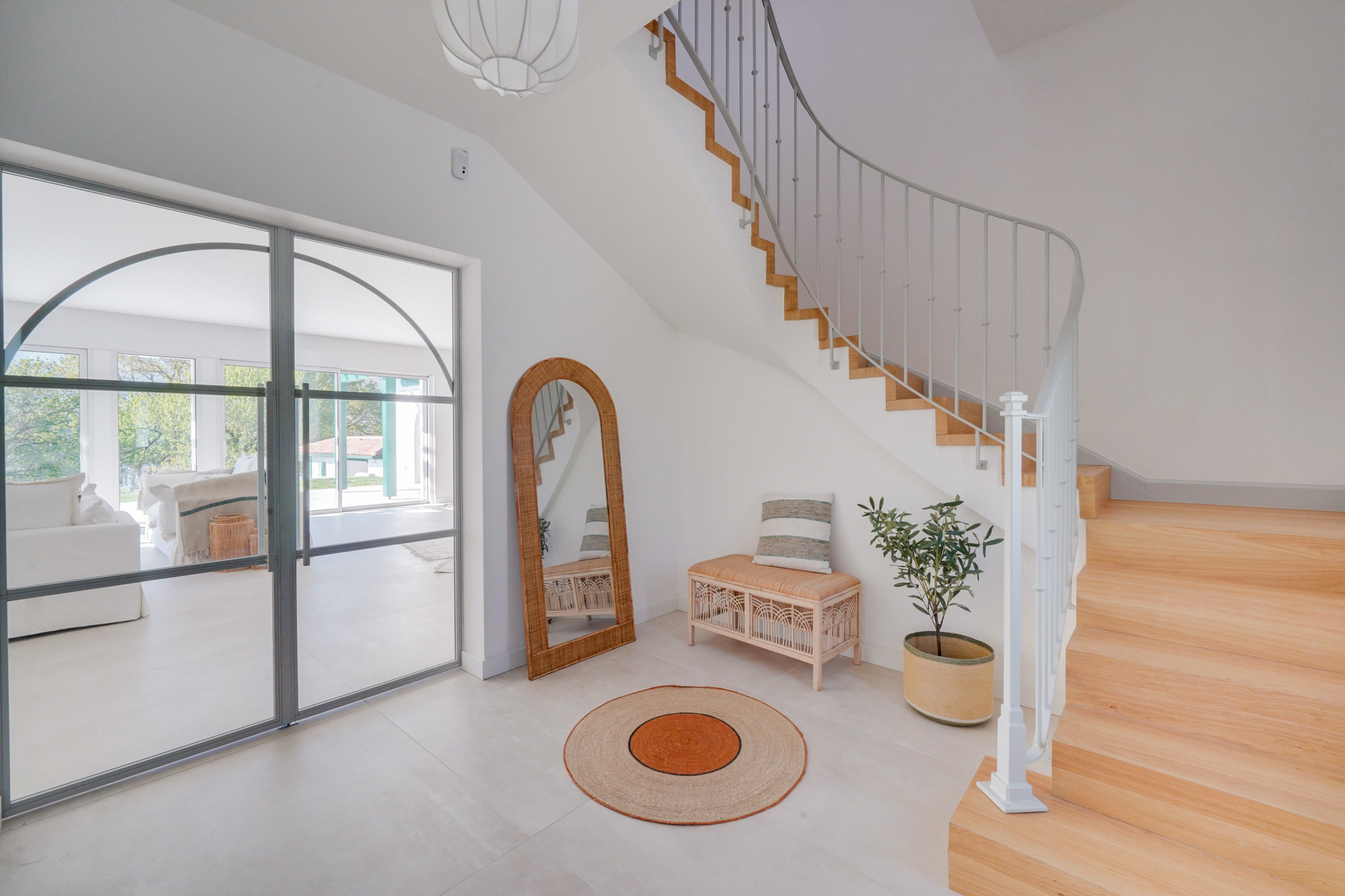 Intérieur d’une maison rénovée Intérieur d'une maison moderne avec un escalier en bois et un miroir, éclairage naturel.