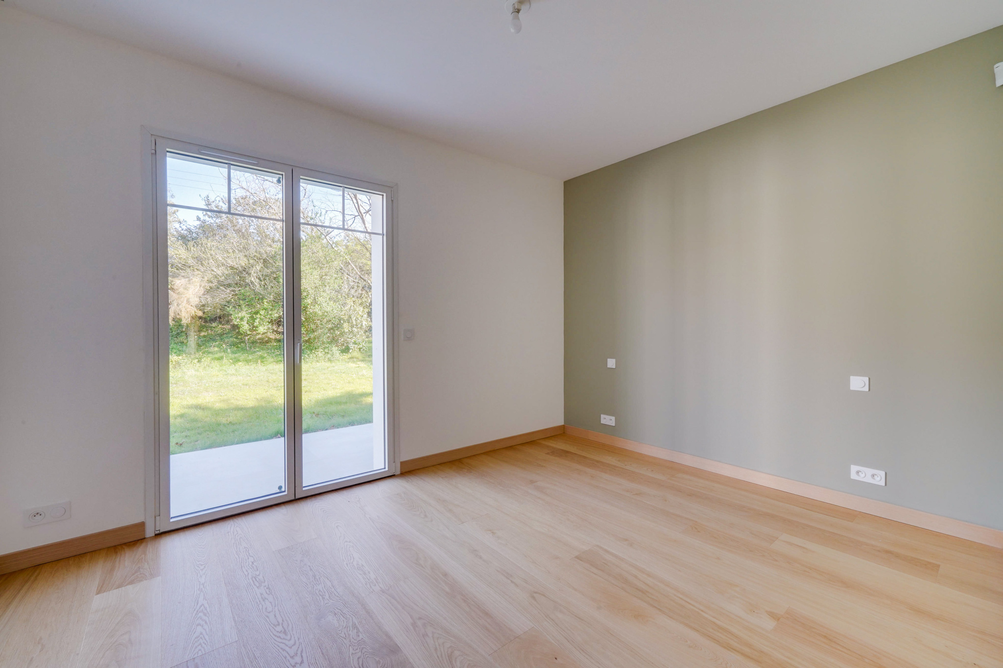 Intérieur d’une maison à Urrugne Intérieur d'une maison rénovée avec un sol en bois et des fenêtres donnant sur un jardin.