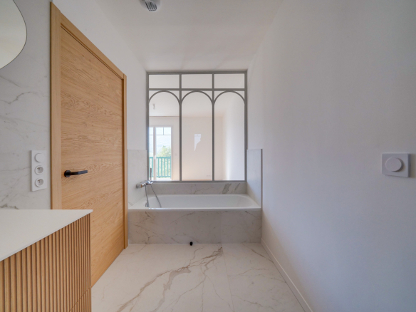 Salle de bain moderne avec baignoire et miroir décoratif en marbre.