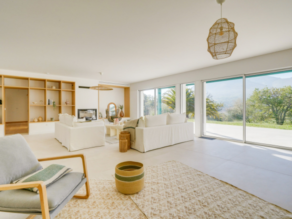 Intérieur d'une maison moderne avec salon lumineux et vue sur la nature.