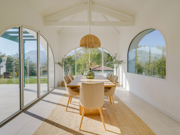 Intérieur d'une maison moderne avec salle à manger lumineuse et grandes fenêtres.