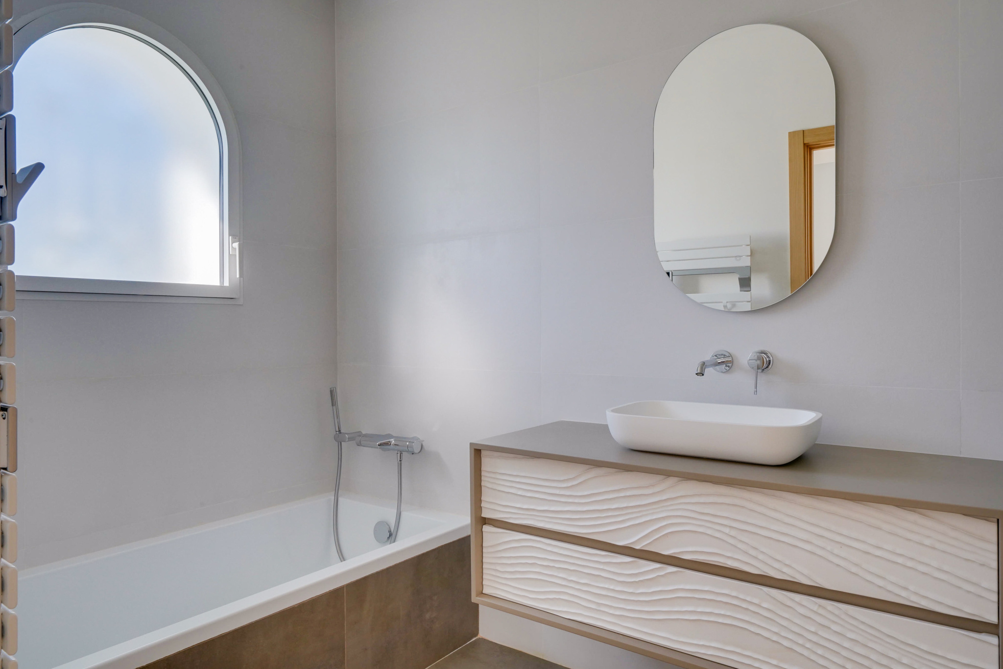 Salle de bain contemporaine Salle de bain moderne avec baignoire, miroir ovale et meuble sous lavabo.
