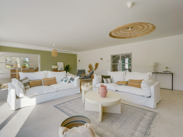 Intérieur d'une maison rénovée avec salon lumineux, canapés blancs et décoration moderne.