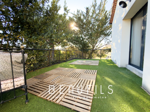 Wooden terrace overlooking a wooded garden, in front of a renovated villa in Frontignan.