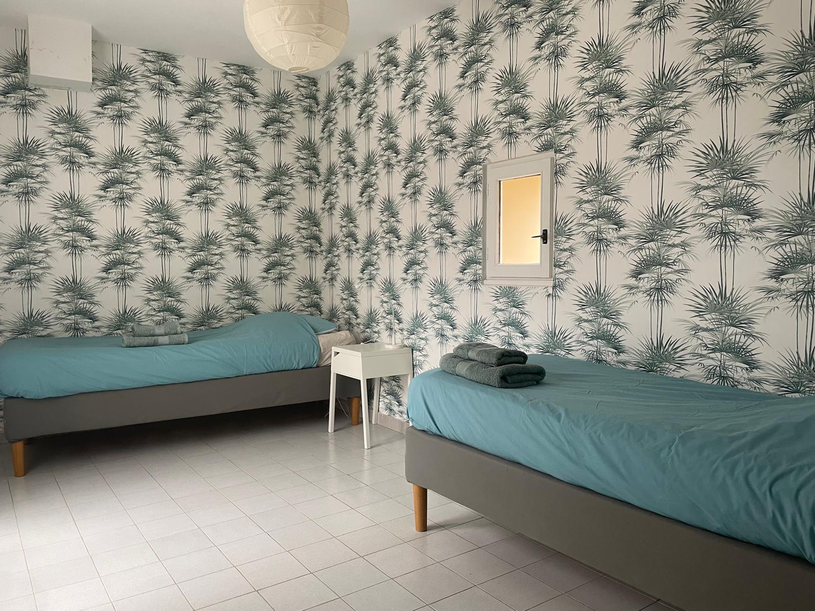 Bed and breakfast in Faucon Guest room with two single beds and wall decoration with palm tree motifs.