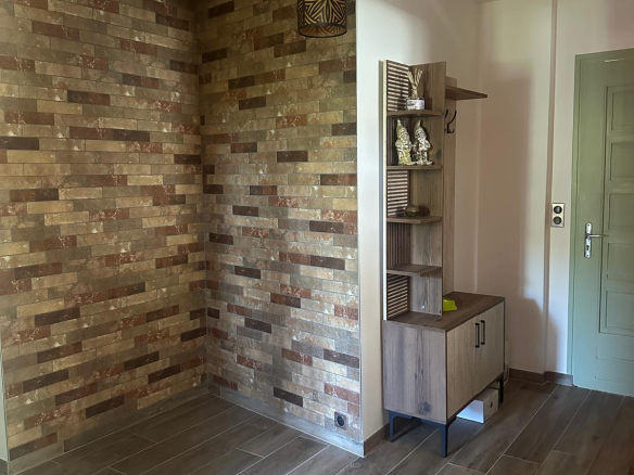 Interior of a property with a stone wall and a wooden piece of furniture, pendant lighting.