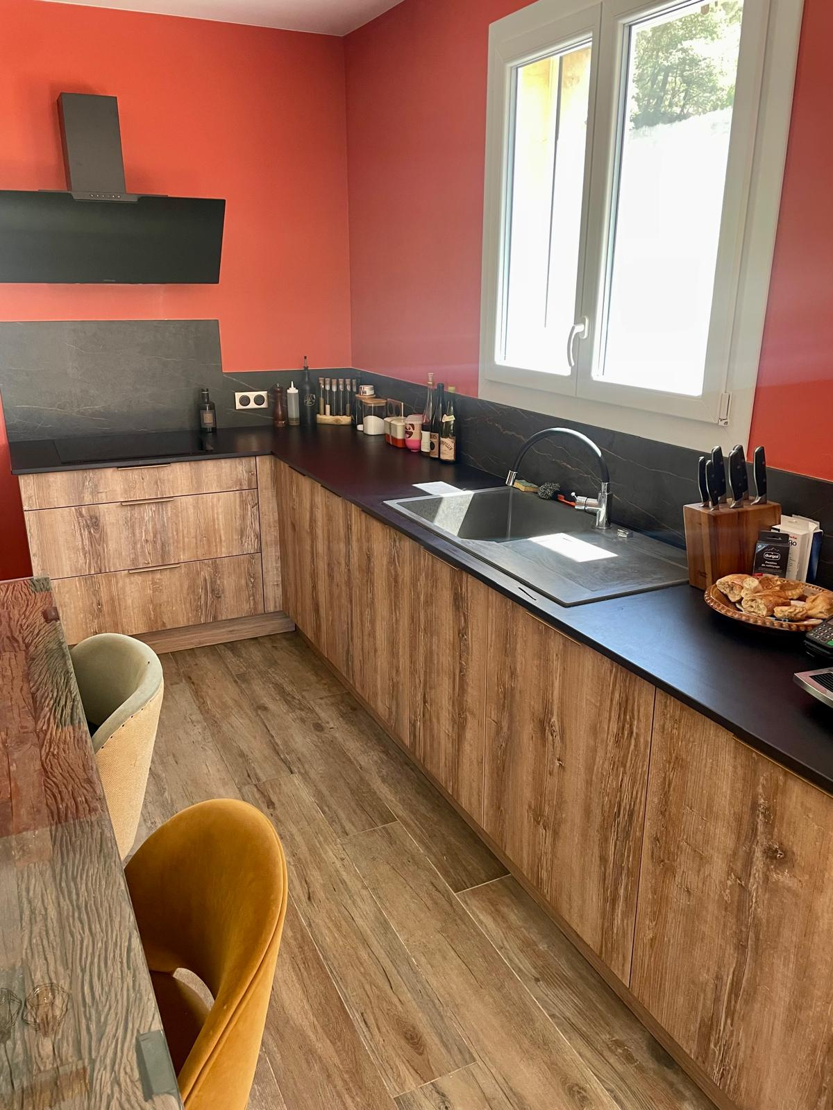 Kitchen at the property in Faucon Modern kitchen with wooden furniture and red wall, equipped for meal preparation.