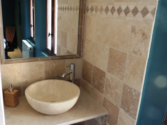 Bathroom with stone sink and beige tiled walls.