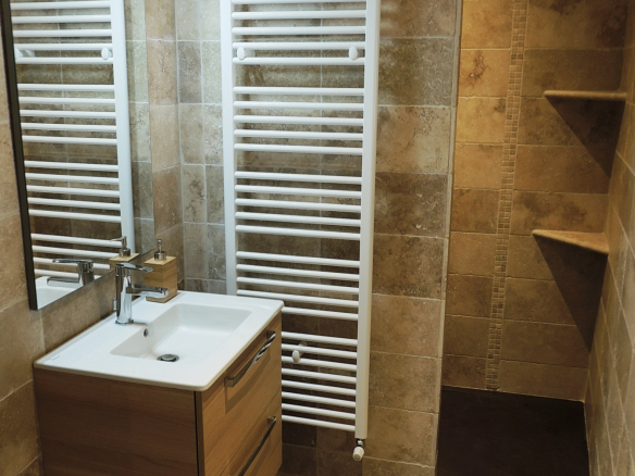 Modern bathroom with shower, sink and towel warmer.