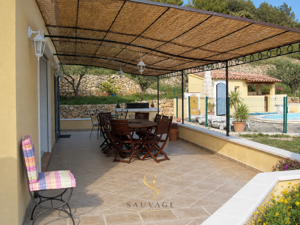 Covered terrace with wooden furniture and swimming pool in the background, Draguignan.