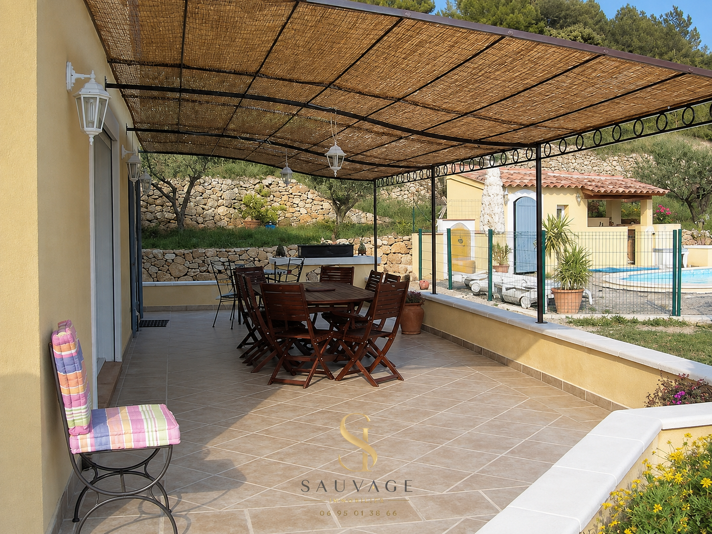 Covered terrace with wooden furniture and swimming pool in the background, Draguignan.