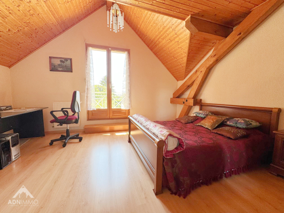 Spacious room with bed and desk under a wooden ceiling in Sergy.