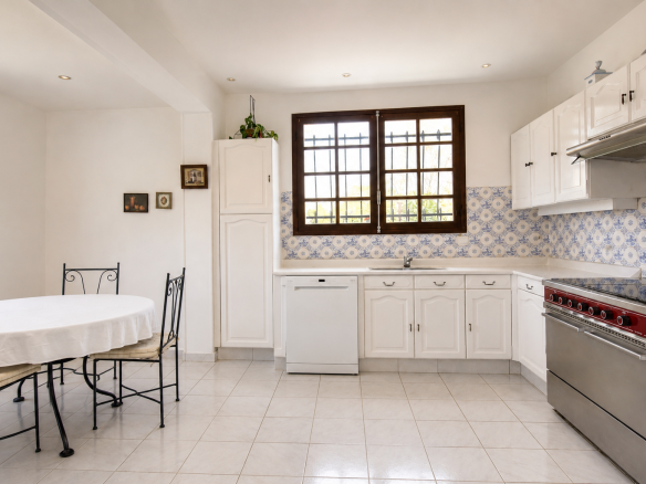 Bright kitchen with table and chairs, light-colored tiles, and small-paned windows.