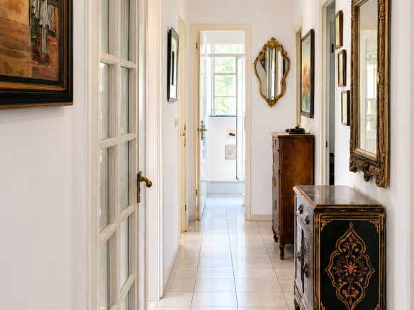 Interior of a house with a bright hallway, paintings and antique furniture.