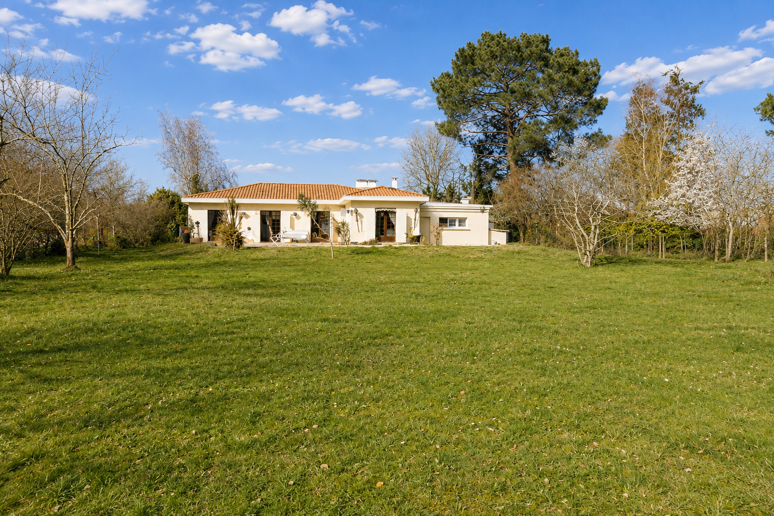 Property in Gradignan Single-storey house in Gradignan on a wooded plot with swimming pool, blue sky and clouds.