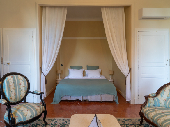 Room in a restored castle with a double bed and armchairs, tastefully decorated.