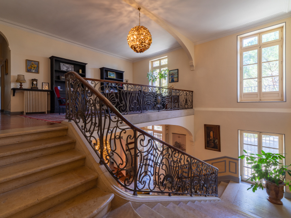 Interior of the castle with a stone staircase and elegant decoration, natural light through the windows.